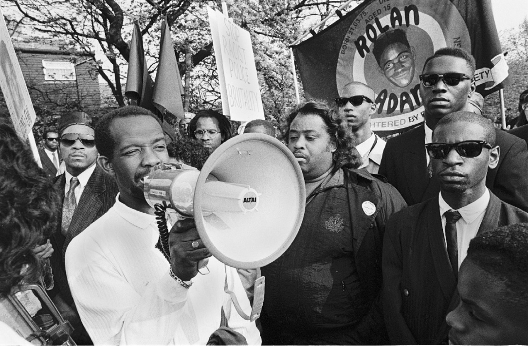 Richard Adams (with megaphone), father of murdered teenager Rolan Adams at the 1991 march demanding the closure of the British National Party offices in Thamesmead. To Mr Adams’ left is US Civil Rights activist Al Sharpton. UK tabloid questioned Mr Sharpton’s right to support the Adams family and labelled him a “rabble rouser” who was “stirring up hatred”.